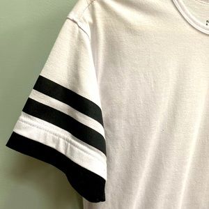 Men’s long hem short sleeve with black stripes around the end of sleeves.